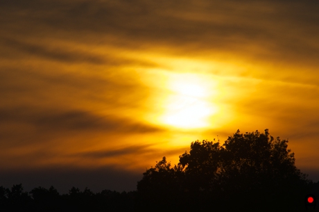 雲に霞ながら沈む太陽の写真