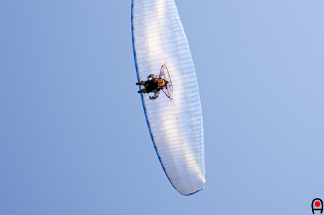 真上を飛ぶモーターパラグライダーの写真